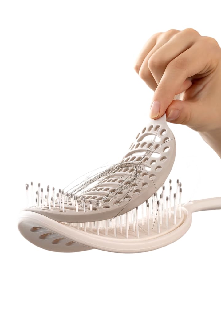 Self-cleaning hair brush with its flexible cleaning pad lifted to remove collected strands